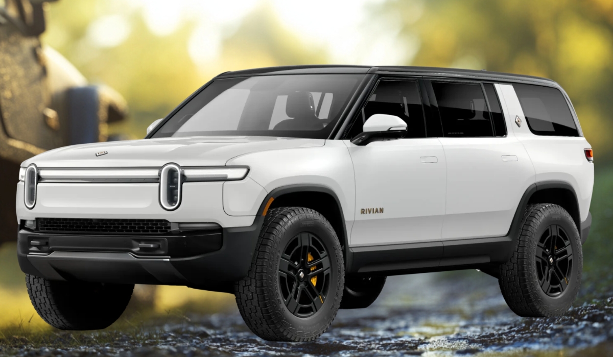 White Rivian R1S electric SUV with black roof and yellow brake calipers parked on a scenic forest trail at sunrise