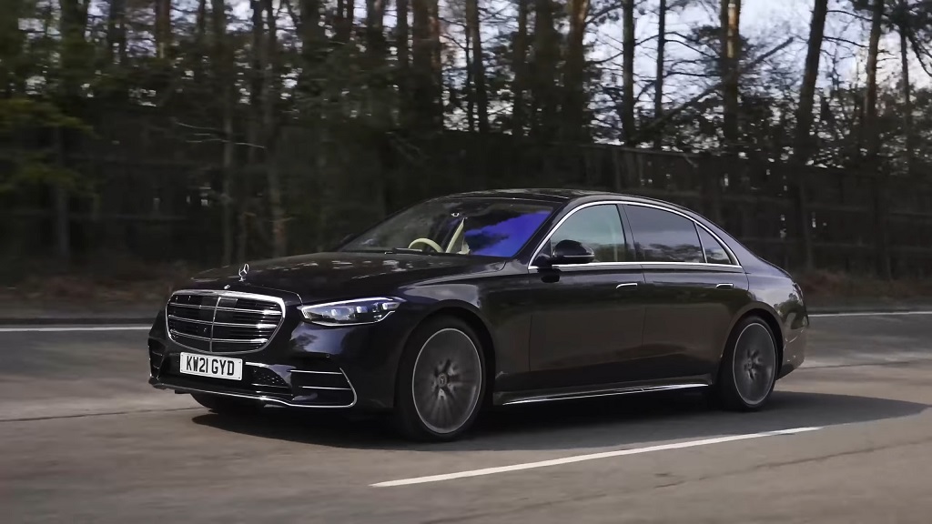 Black Mercedes-Benz S-Class luxury sedan driving on a road, side view