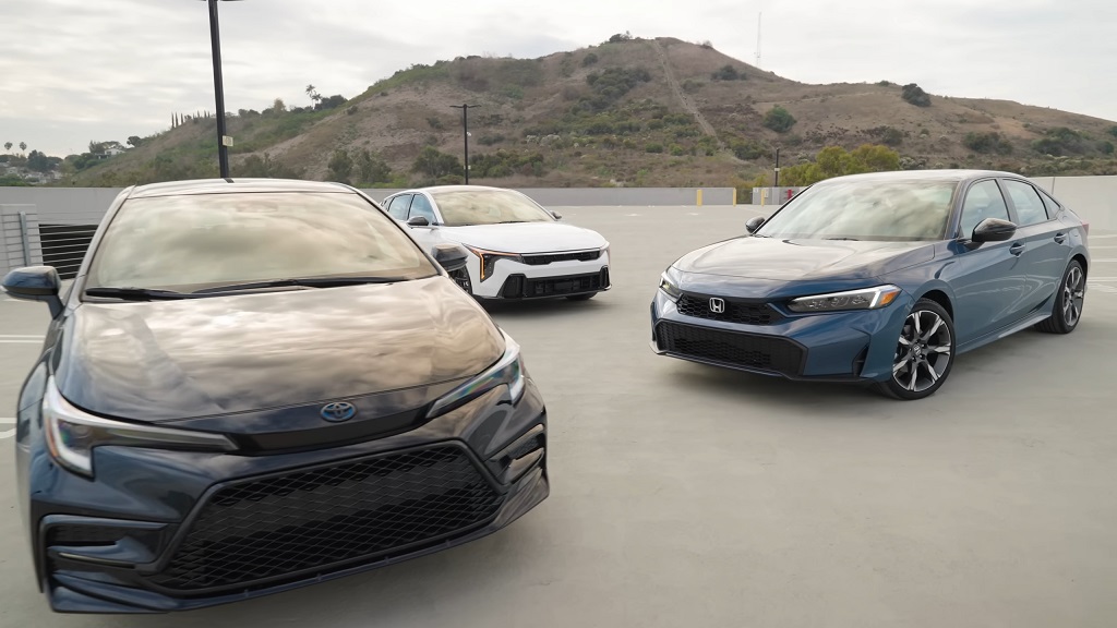 Toyota Corolla Hybrid, Honda Civic Hybrid, and Kia K4 sedans parked side by side in an outdoor lot